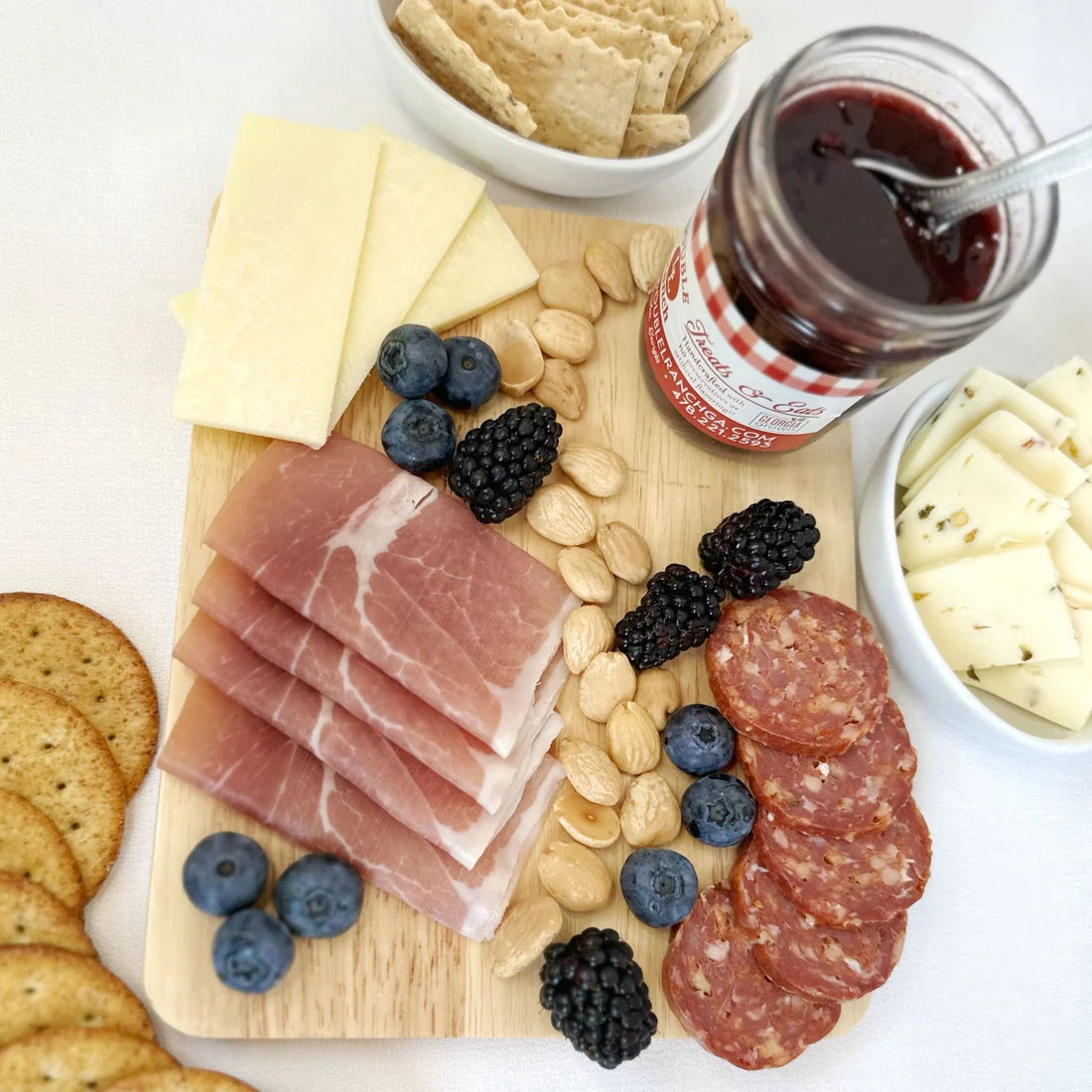 Double L Ranch Blackberry Jam jar on a charcuterie board with assorted cheeses, fruits, and nuts