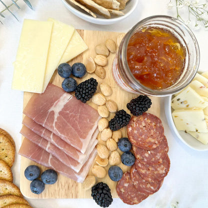 Double L Ranch Caramel Apple Jam jar on a charcuterie board with assorted cheeses, fruits, and nuts