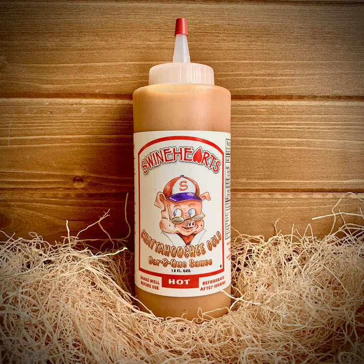 Front view of the Hot Swinehearts Sauce placed on hay with a wooden backdrop