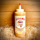 Front view of the Mild Swinehearts Sauce placed on hay with a wooden backdrop